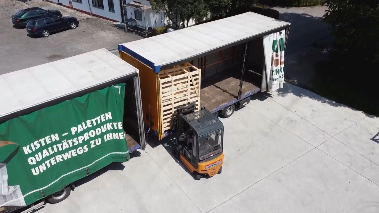 Stapler verlädt Holzkisten auf einen Lastwagen, von oben gefilmt